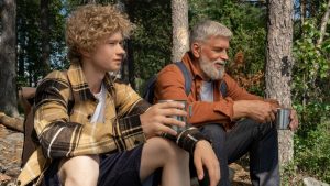 A grandfather and grandson enjoying a break in the forest, sipping from tin cups.